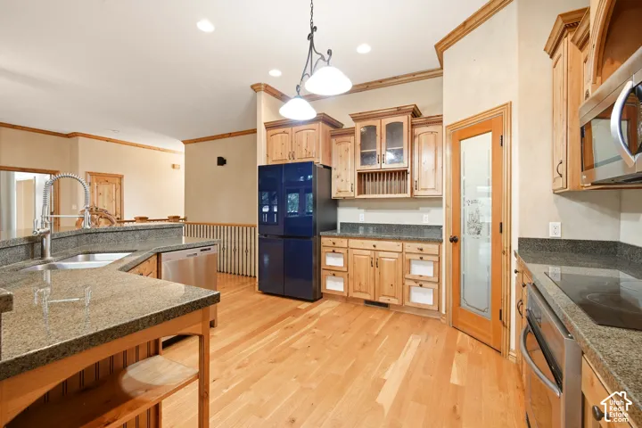Kitchen featuring natural wood-finish cabinetry, solid surface countertops, hardwood flooring, recessed lighting, and a pantry with a decorative glass panel door