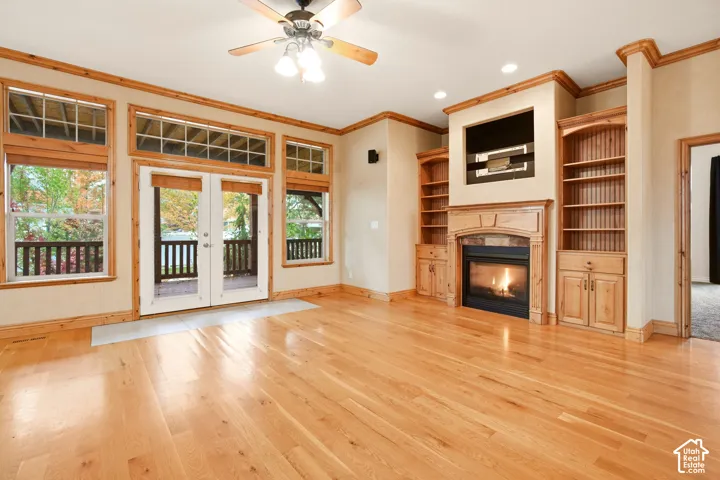 Living area featuring wood-finish flooring, a built-in fireplace with custom cabinetry, and large windows with transoms