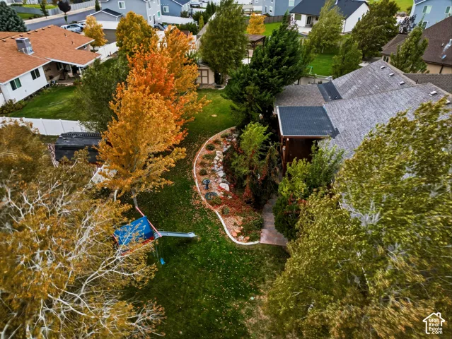 Backyard featuring a landscaped rock garden, curved concrete curbing, mature trees, and a vinyl perimeter fence