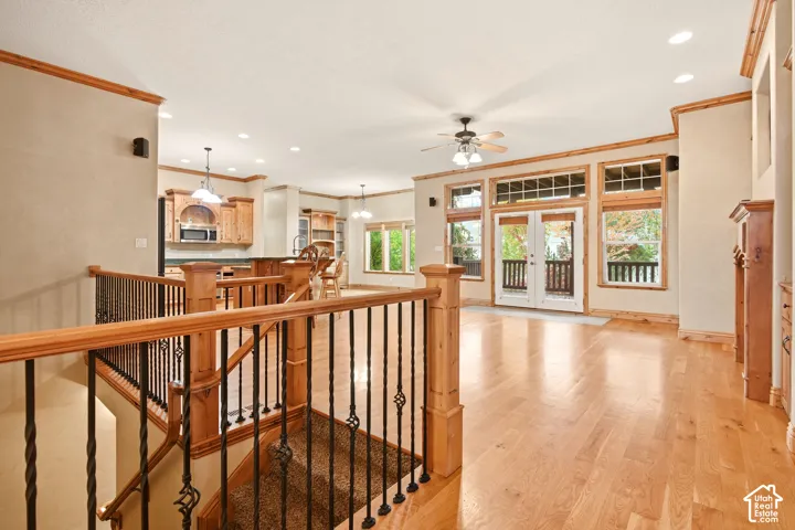 Open-concept area featuring wood-finish flooring, recessed lighting, double glass-paneled doors with transom windows, and a staircase with wood railings and wrought iron balusters