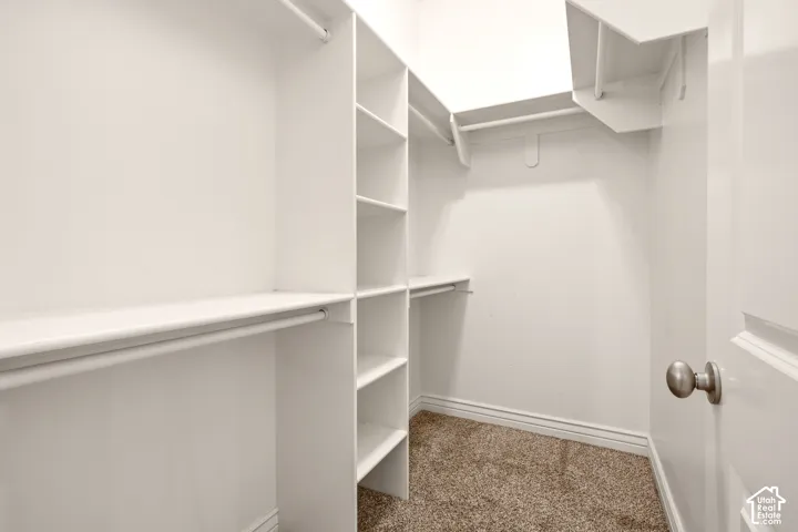 Walk-in closet featuring white built-in shelving, vertical storage towers, and multiple hanging rods