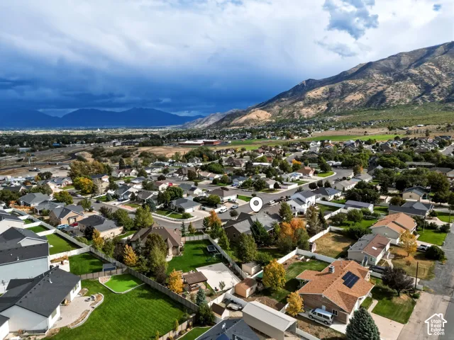 Aerial perspective of a residential property featuring a composition shingle roof, solar panel installation, and a fenced backyard