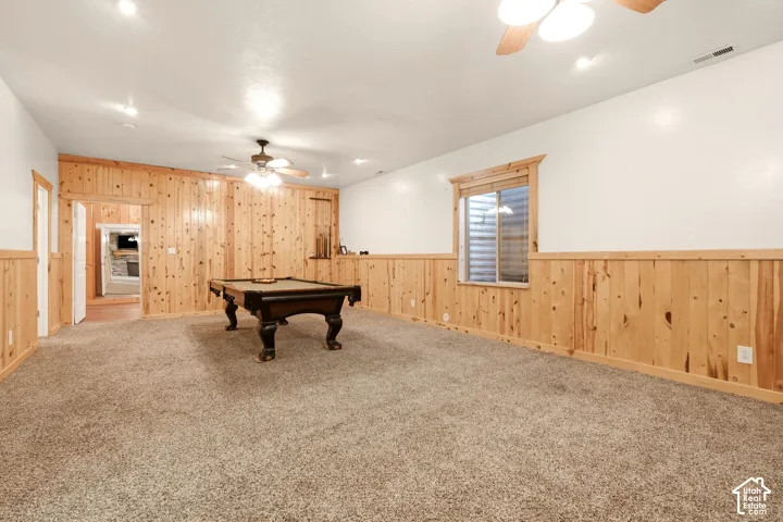 Interior space featuring natural knotty wood wainscoting and wall paneling, neutral wall-to-wall carpeting, recessed ceiling lighting, and a ceiling-mounted light fixture with a fan
