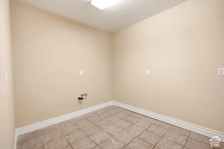 Dedicated utility space featuring neutral-toned walls, tile flooring, and integrated plumbing hookups