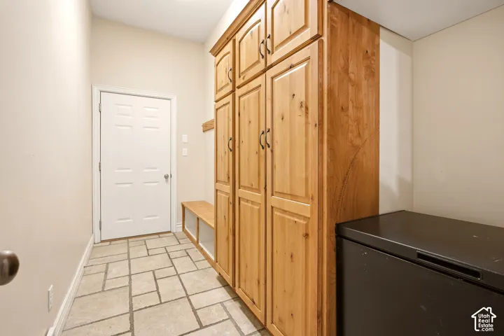 Custom wood cabinetry with integrated storage and bench seating, complemented by stone-tiled flooring and a panel door