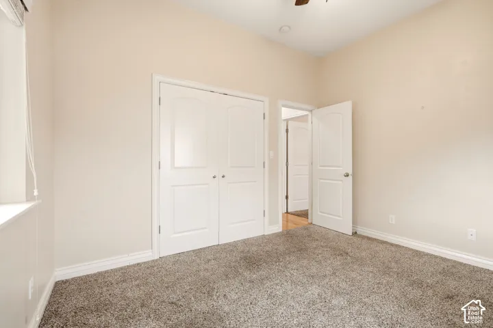 Neutral-toned room featuring textured carpeting, dual-panel closet doors, and solid-core interior doors with metallic hardware