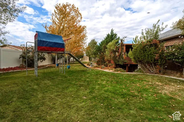 Expansive backyard featuring a fenced perimeter, tiered landscaping, and a multi-level wooden deck