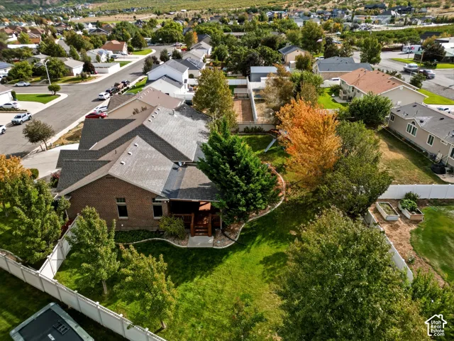 Brick exterior featuring an elevated wood deck, expansive lawn, mature landscaping, and vinyl perimeter fencing