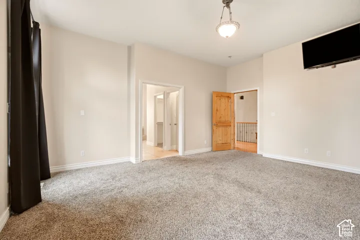 Room featuring high ceilings, neutral wall tones, wall-to-wall carpeting, a traditional hanging pendant light fixture, and solid wood doors