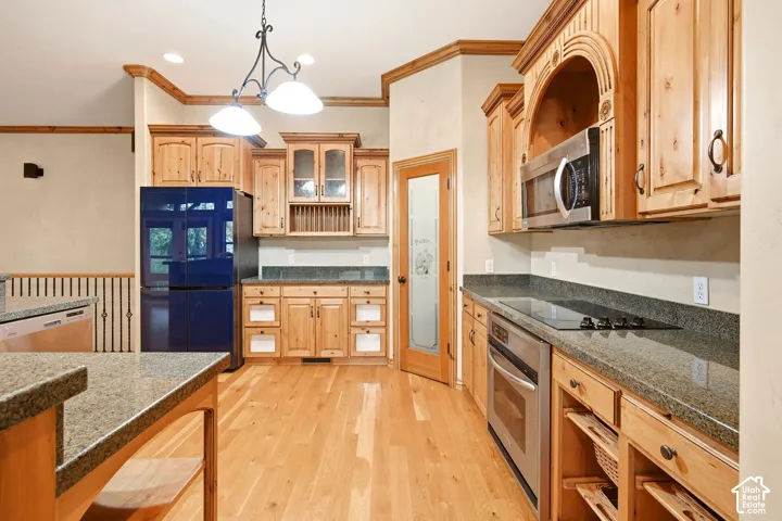 Kitchen featuring natural-finish wood cabinetry, stone countertops, stainless steel appliances, wood-finish flooring, and a pantry with a frosted glass door