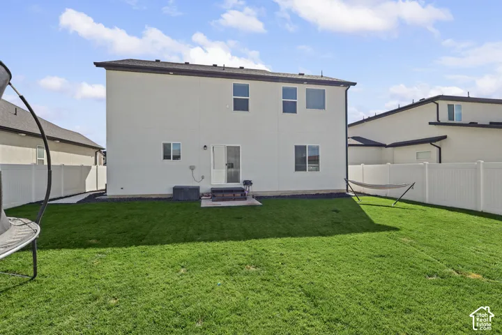 Rear exterior featuring a smooth stucco facade, multi-level architectural design, sliding glass door, and a private yard enclosed by vinyl privacy fencing