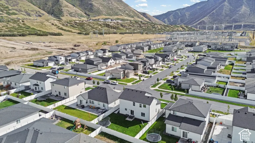 Aerial perspective of residential neighborhood featuring multi-level dwellings, asphalt streets, white perimeter fencing, and mountain backdrop