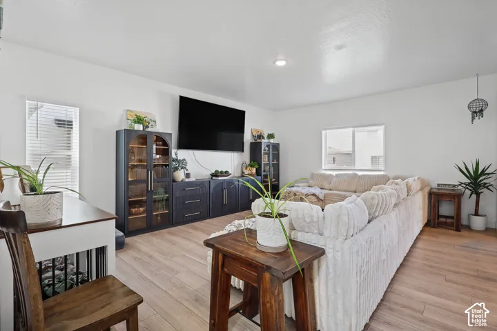 Living area featuring wood-finish flooring, recessed lighting, and built-in dark-toned cabinetry with glass-front display doors