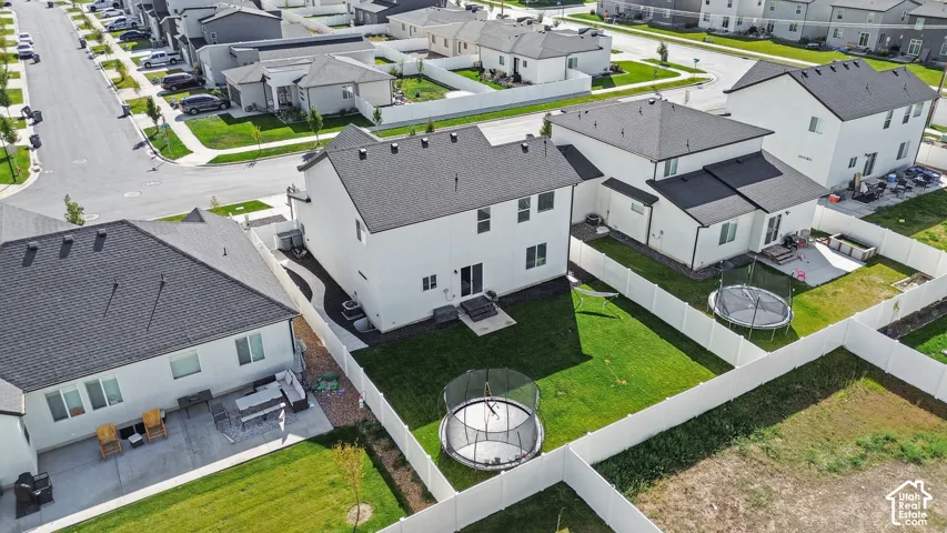 Two-story residential exterior featuring a light-toned facade, shingled roof, fenced rear yard, and concrete patio