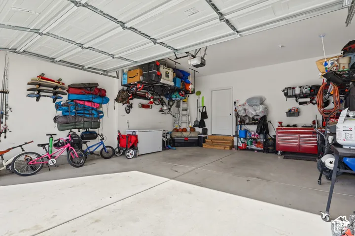 Garage featuring concrete flooring, a paneled overhead door, built-in overhead storage racks, and a dedicated interior entry door