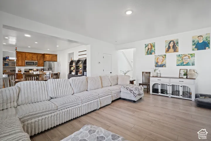 Open-concept interior featuring wood-finish flooring, recessed lighting, and kitchen cabinetry with stainless steel appliances
