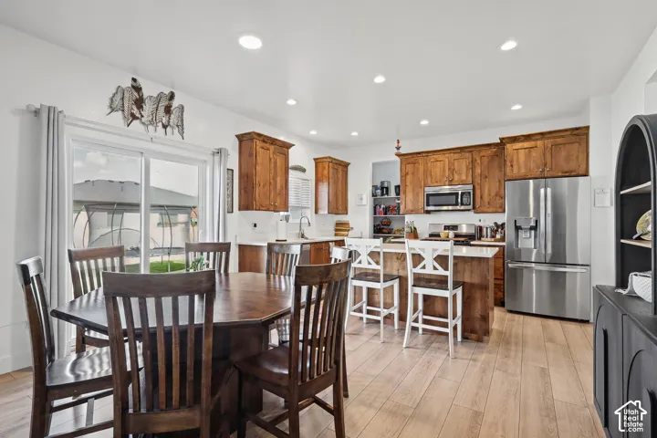 Kitchen featuring natural wood-finish cabinetry, solid-surface countertops, recessed lighting, and stainless steel appliances, complemented by wood-finish flooring