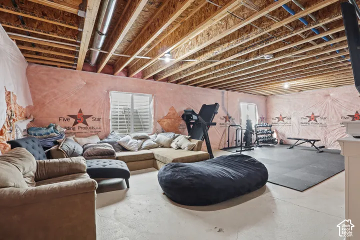 Unfinished flex space featuring concrete flooring, exposed ceiling joists, and two egress windows
