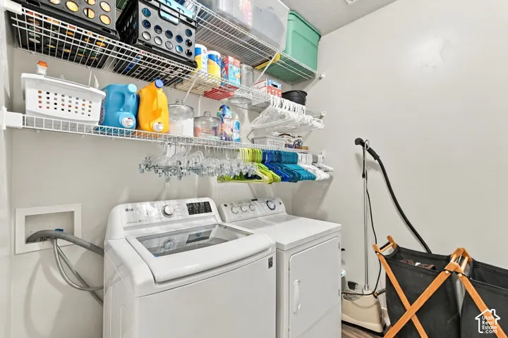 Laundry area featuring white walls, wire shelving, a front-load washing machine, and a dryer