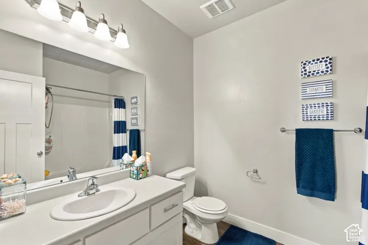 Bathroom featuring a single vanity with a white countertop, an undermount sink, and a chrome faucet