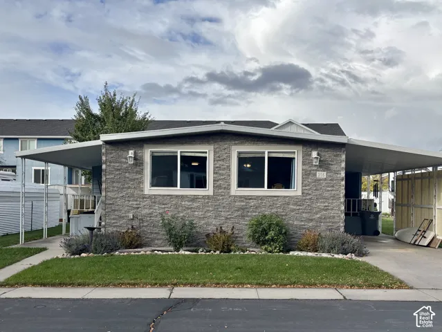 Exterior featuring a stacked stone facade, dual covered carports, and low-maintenance landscaping