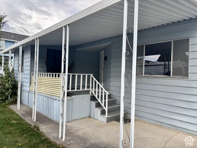 Exterior featuring horizontal siding, a covered porch with decorative metal supports, metal railing, and concrete steps