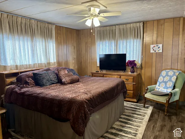 Interior space featuring wood-paneled walls, wood-finish flooring, and a ceiling-mounted light fixture with an integrated fan