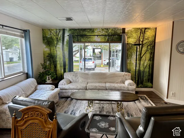 Living area featuring large windows with natural light, wood-finish flooring, and a forest-themed accent wall