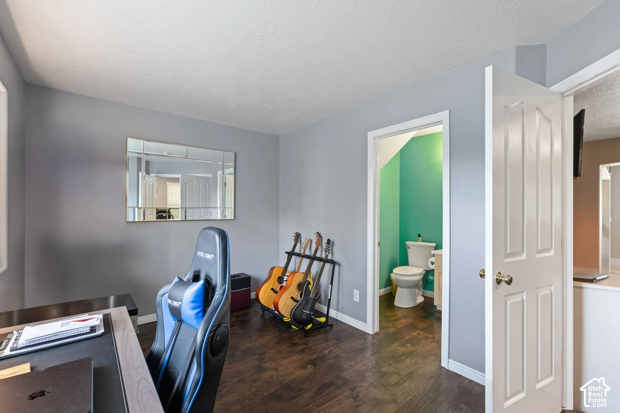 Room featuring dark wood-finish flooring, a wall-mounted rectangular mirror, and an interior four-panel door