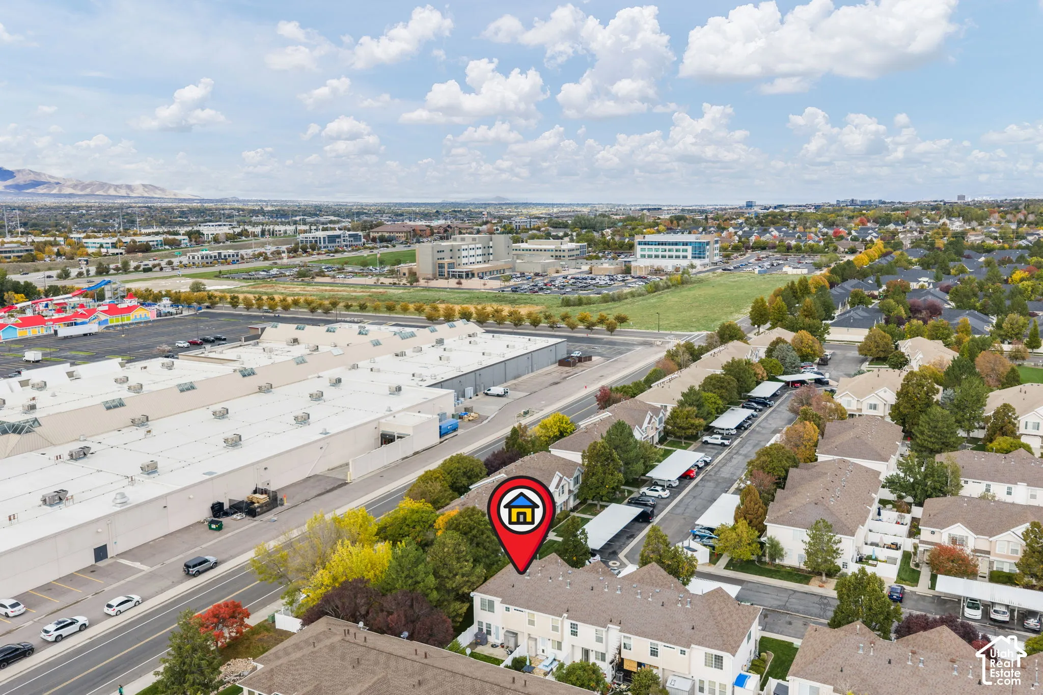 Aerial perspective of multi-level residential structure featuring asphalt shingle roofing, exterior stucco finish, and covered parking areas