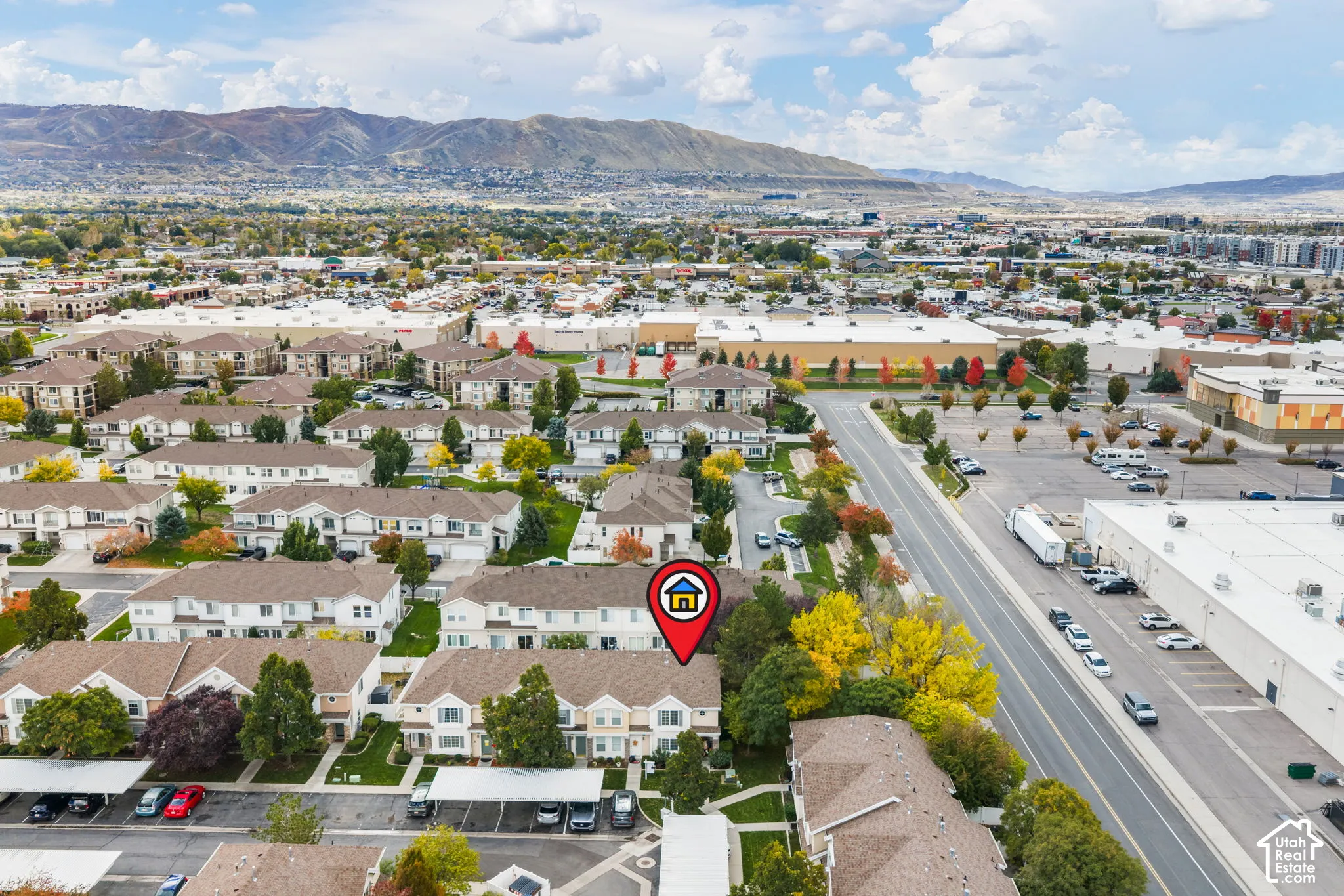 Aerial perspective of multi-family residential structures featuring shingled rooflines, exterior siding, and assigned carport parking, set against a backdrop of mountain terrain