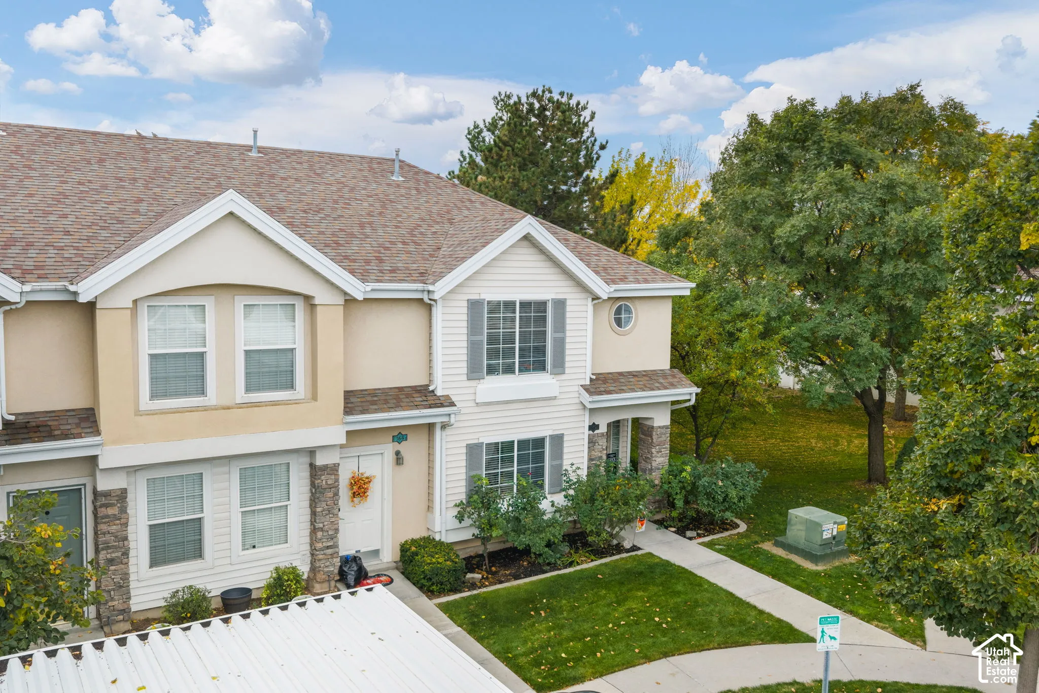 Multi-story exterior featuring a mix of horizontal siding and stone veneer, gabled rooflines, decorative shutters, and established landscaping
