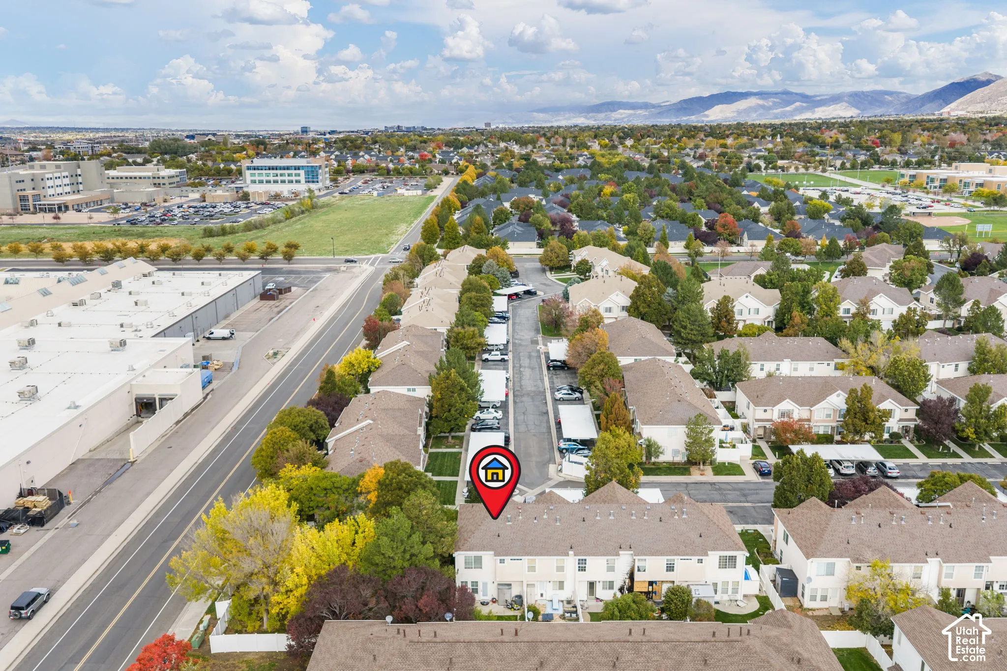 Aerial perspective featuring multi-story residential architecture with shingled rooflines, paved surface parking, and perimeter landscaping set against a mountain backdrop