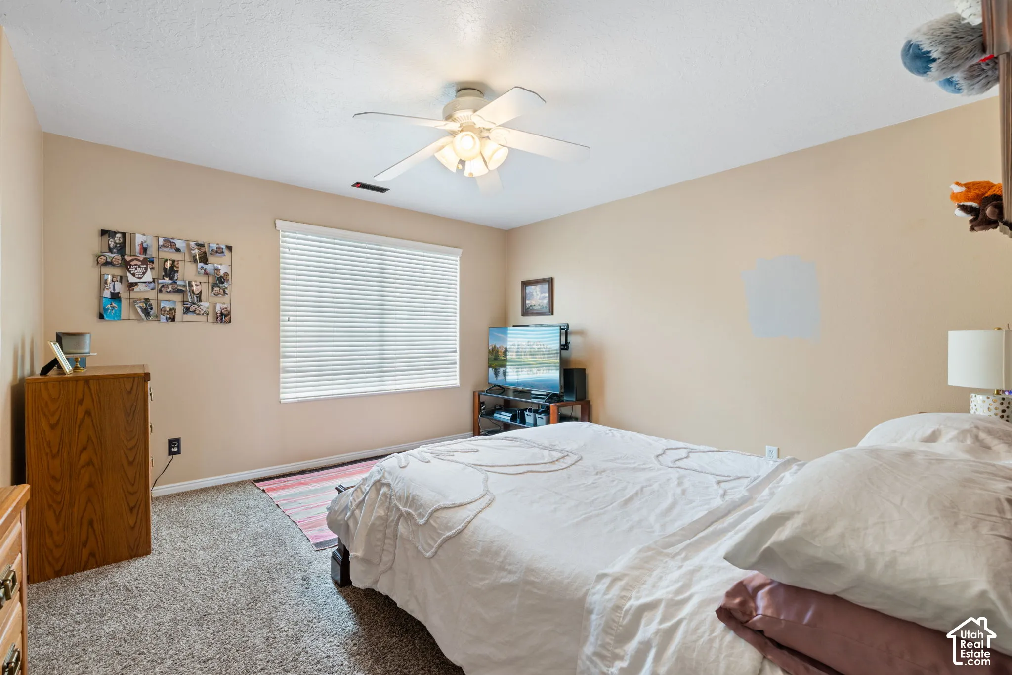Neutral interior featuring carpeting, a multi-blade ceiling fan with integrated lighting, and a window with horizontal blinds
