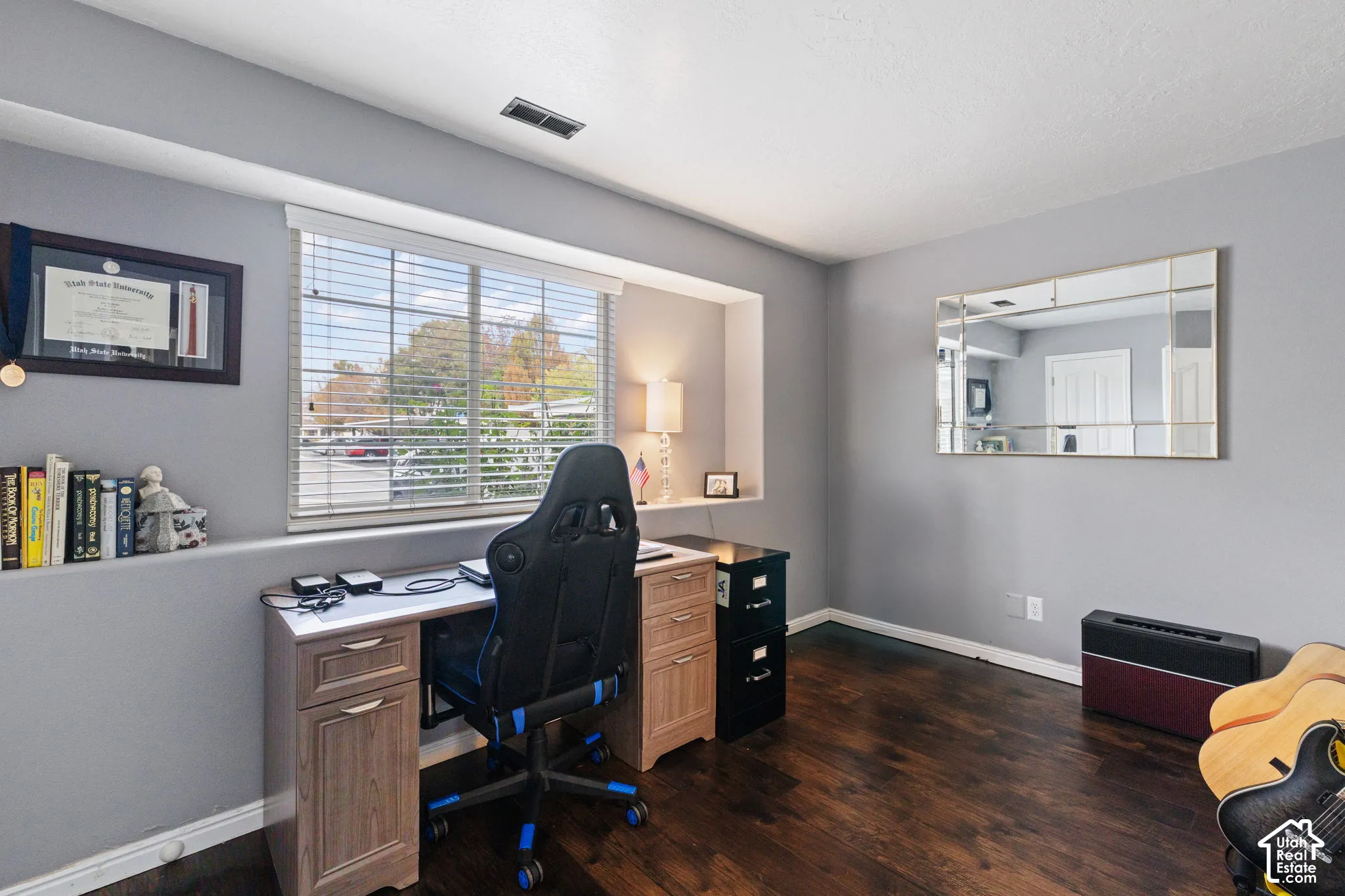 Room featuring wood-finish flooring, a deep-set window alcove, and a large decorative wall-mounted mirror