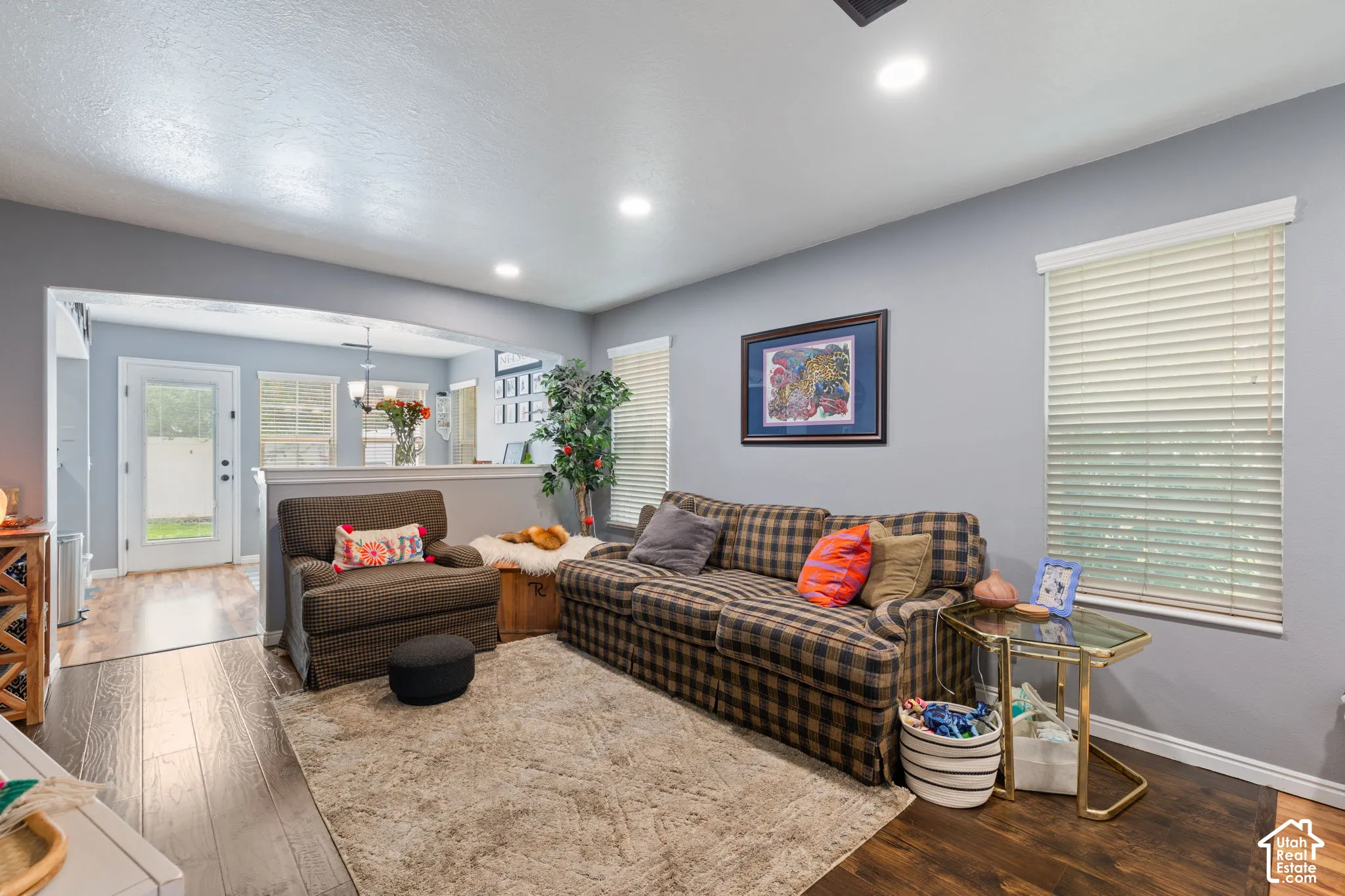 Living area featuring wood-finish flooring, recessed lighting, and windows equipped with horizontal blinds