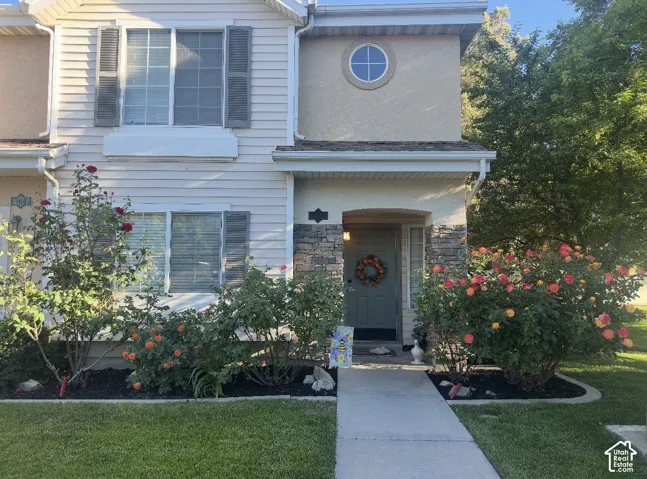Exterior facade featuring horizontal lap siding, stone veneer accents, decorative shutters, a circular accent window, and a paved walkway