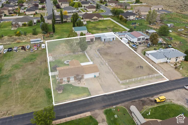 Expansive lot featuring a fenced pasture area, mature trees, concrete driveway, and attached garage