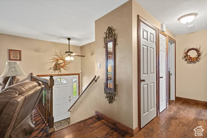 Wood-finish flooring, staircase with wood railings, white panel doors, and ceiling-mounted light fixtures
