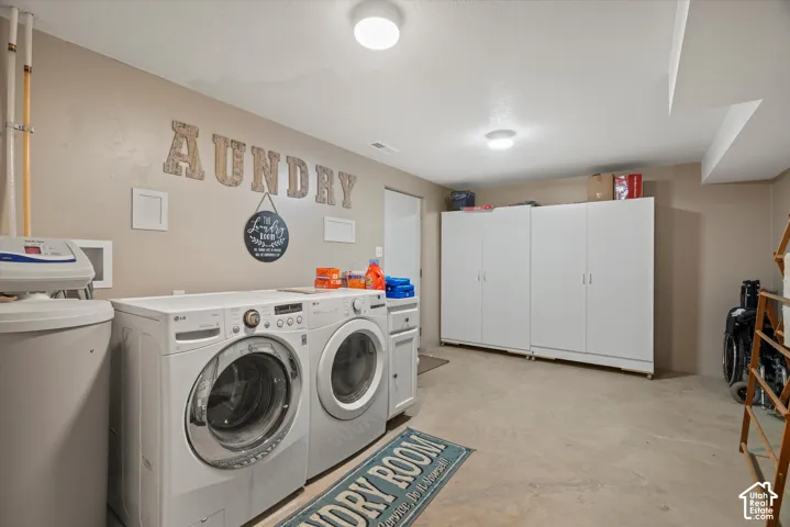 Laundry area featuring dual white storage cabinets, ceiling-mounted flush lighting, and a water softening system