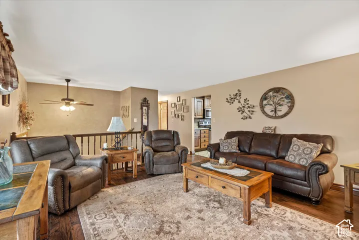 Living area featuring wood-finish flooring, a ceiling-mounted light fixture with fan, and a wood balustrade