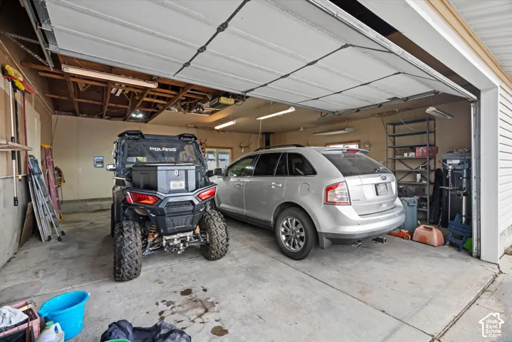 Two-car garage featuring a concrete floor, overhead lighting, and white horizontal siding exterior