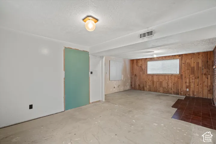 Interior space featuring vertical wood-panel wall cladding, ceramic tile floor inset, and a single globe-style flush mount ceiling light