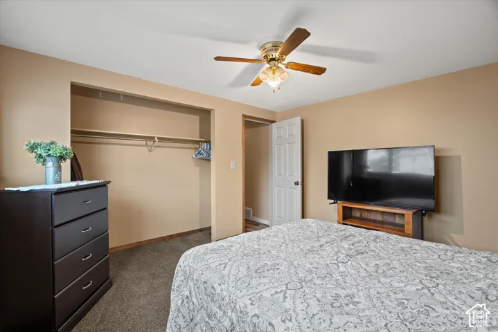 Room featuring wall-to-wall carpeting, a ceiling-mounted light fixture with fan, a six-panel interior door, and a built-in closet with a shelf and hanging rod
