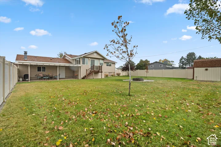 Fenced backyard featuring a covered patio, fire pit, and detached storage shed