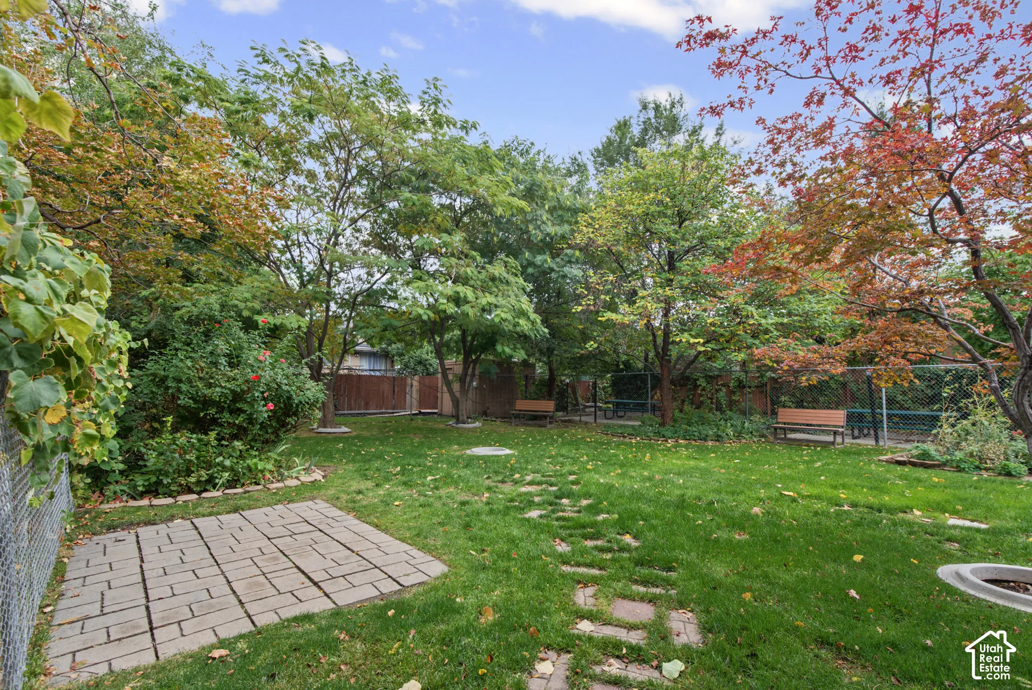 Shared Dog Run featuring a manicured lawn, stone paver patio, stone path, mature deciduous trees, and wood fencing