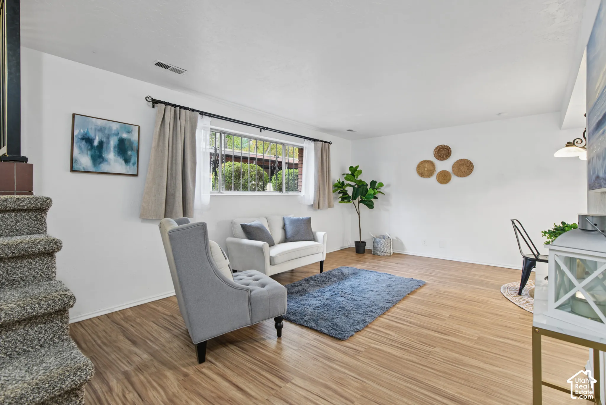 Interior space featuring wood-finish flooring, a large window with horizontal muntins, and carpeted stairs