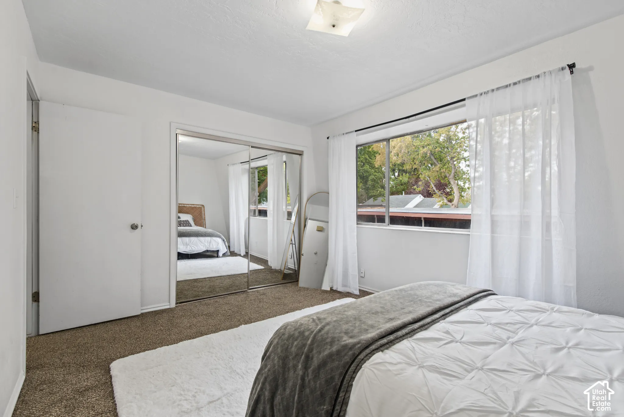 Wall-to-wall carpeting, mirrored sliding closet doors, flush-mount ceiling light fixture, and large dual-pane window