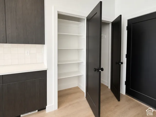 Built-in cabinetry featuring a matte dark finish, light-toned countertop, square-tile backsplash, and solid-core paneled doors with matte black hardware