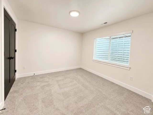 Neutral-toned carpeting, matte black dual-door entry, window with integrated security grate, and ceiling-mounted LED lighting